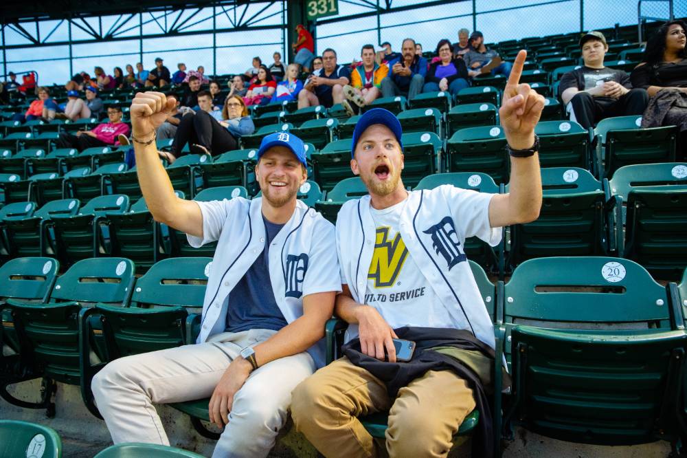 Photo of two young men cheering and wearing Tigers and GVSU gear